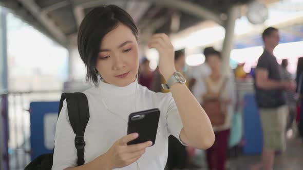 Portrait of asian woman with earphone listening music and using smartphone for chatting