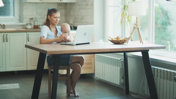 Woman With A Little Child Up To A Year Old At Home In The Kitchen alt