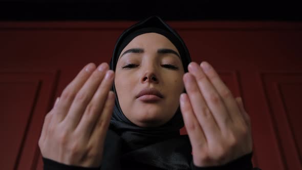 Young Muslim Woman in Hijab Raises Her Hand and Prays