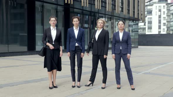 Serious Company Staff Standing and Crossing Hands Next To Office. Group of Successful Women Workers