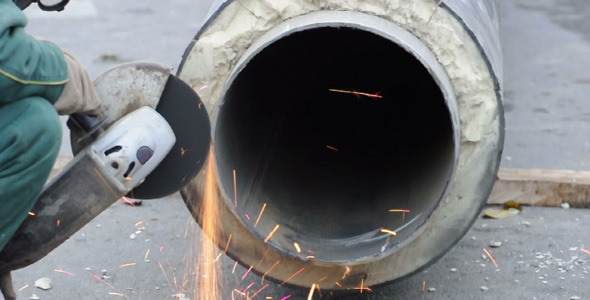 Worker cutting pipe with grinder