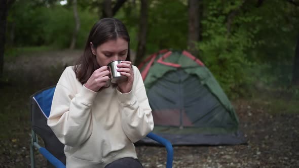 Woman Backpacker Drinks From a Hot Mug in the Forest