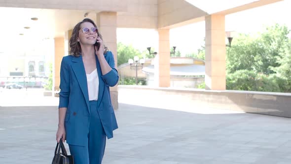 Woman in a Business Suit Smiles While Talking on the Phone. alt