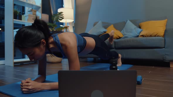 Asia lady in sportswear exercises doing work out and using phone to watch yoga video tutorial.