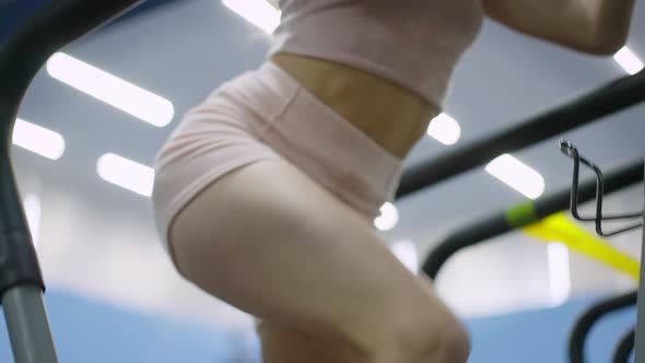 Camera Goes Up As Slim Fit Blond Young Woman Working Out on Exercise Machine in Gym alt