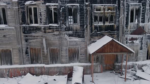 Burned Wooden House After Fire in Winter Covered with Icicles