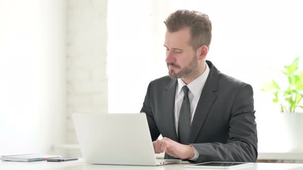 Young Businessman Showing Thumbs Down Sign While Using Laptop in Office alt