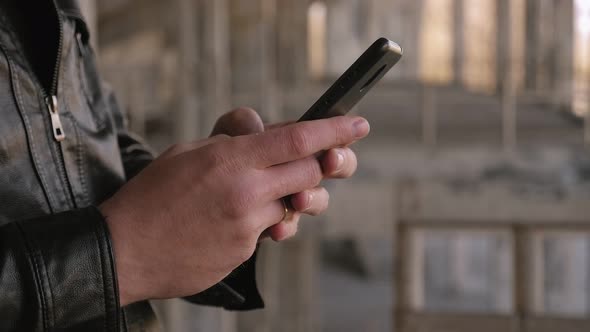 Closeup of a Man's Hand with a Phone Against the Background of an Old Building alt