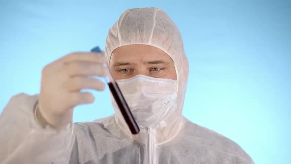 Man in Protective Suit Mask Gloves Holds and Drops Test Tube with Coronovirus