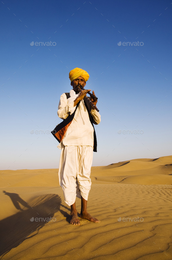 Indigenous Indian Man Playing Wind Pipe In A Desert