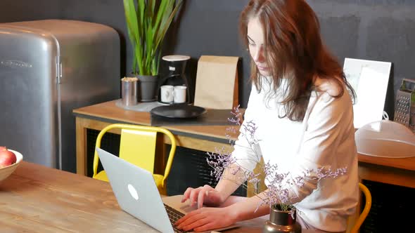 Young Woman Using Laptop at Kitchen