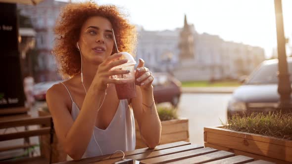 Beautiful Girl Listening Music in Headphones Smiling Resting in Cafe Slow Motion alt