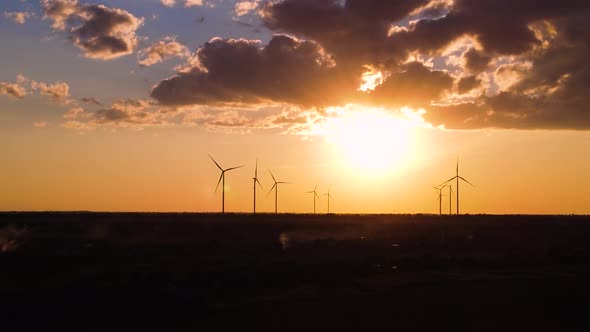 Aerial view of wind power plant on sunset. sea background. 4k drone footage alt
