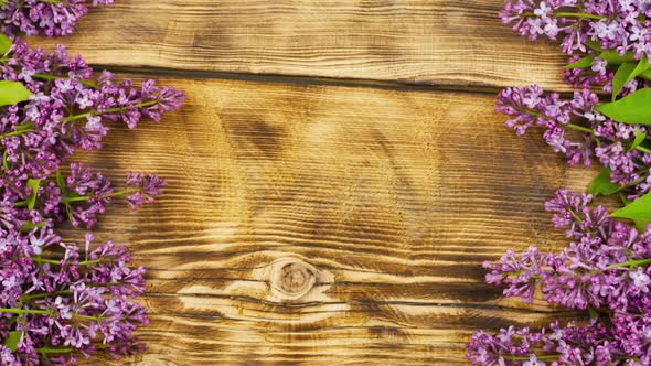 Bouquet of Lilac Flowers Lie on an Old Burnt Wooden Background alt