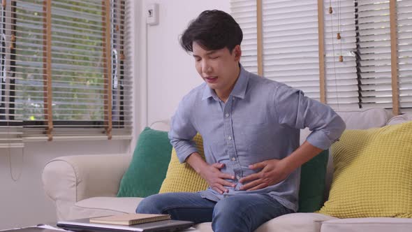 Hand of Asian man holding stomach suffering from pain, diarrhea alt