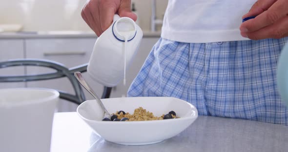 Man pouring milk in a bowl at kitchen 4k