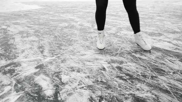 Female legs are ice skating on frozen lake alt