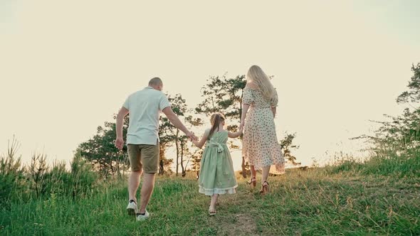 Young Married Couple with Cute Little Girl Spend Time Together Outdoors in the Forest
