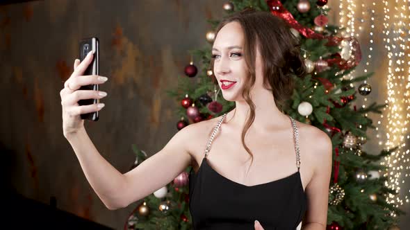 Woman with Hairstyle Talks Via Videocall Near Christmas Tree alt