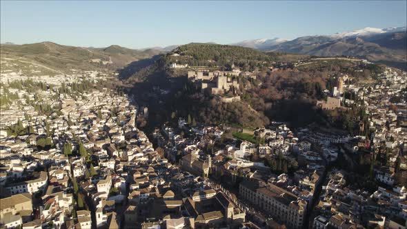Drone flying over Granada city with Alhambra fortress in background, Spain. Aerial forward