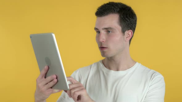 Man Excited for Success While Using Tablet, Yellow Background alt