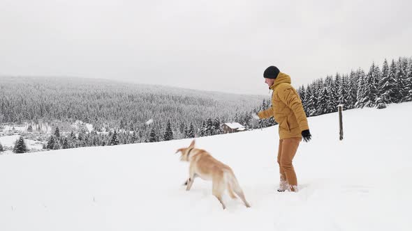 Young Man Throwing Snowball With His Dog