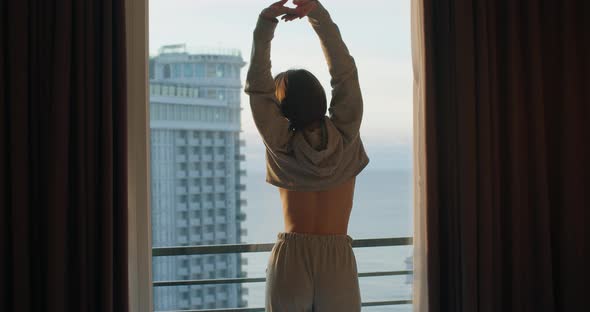 Young Woman Stretching After Waking Up Standing By Window