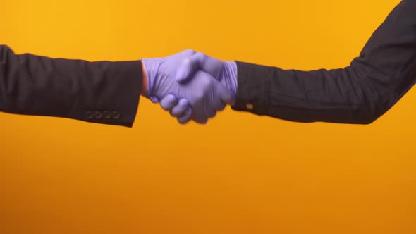 Businessmen Shaking Hands in Medical Gloves on Yellow Background
