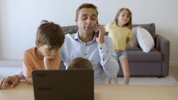 Caring Dad Talking on Smartphone Sitting at Table alt