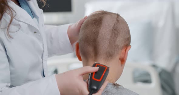 Back View of Kid Sitting in Hospital Ward and Having Hair Cut Preparing for Brain Surgery alt