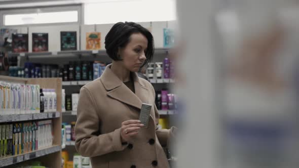 Beautiful Woman Looking at Cosmetics in Supermarket alt