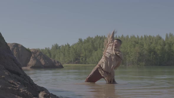A Young Male Shaman Dances a Ritual Dance Standing Kneedeep in a River