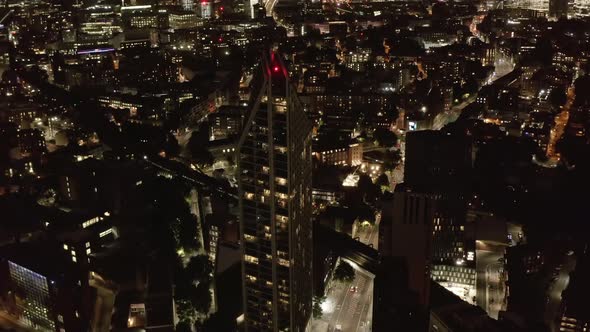 Tilt Up Revealing of Tall Modern Apartment Tower and Night Skyline in Background alt