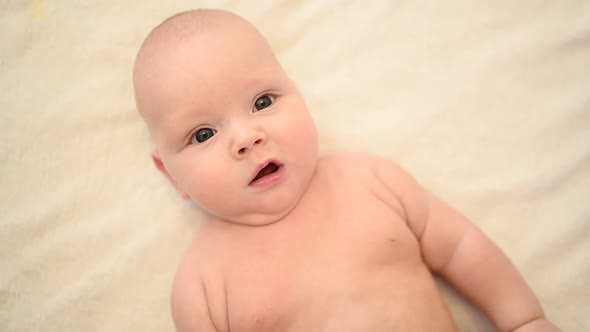 Cute Emotional Funny Smiling Naked Newborn Little Baby Boy Lying on Bed