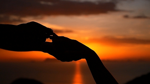 Putting Wedding Ring at Sunset alt