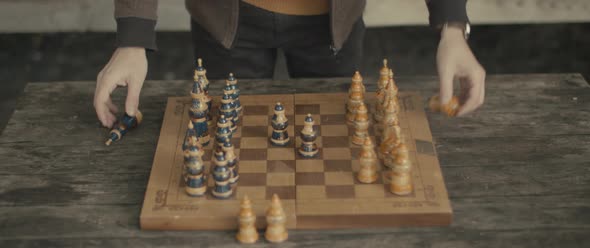 Man hands arrange chess pieces on chessboard on wooden table