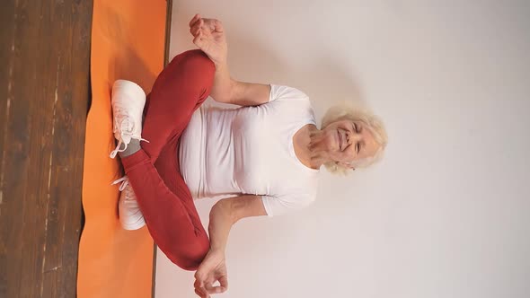 an Elderly Lady Does Yoga on a Fitness Mat at Home in Her Free Time for Health