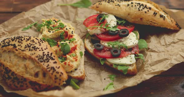 Two Delicious Sandwiches with Hummus, Tomato, Mozarella Cheese, Herbs and Olives alt