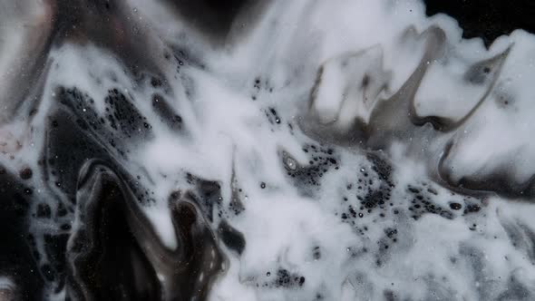 White Paint Spreads on a Black Goldglittering Moving Background alt