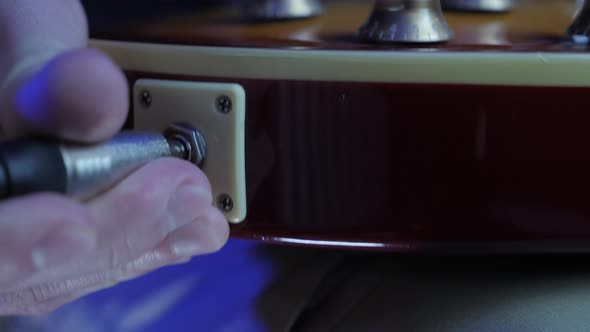 Guitarist unplugs instrument cable jack from electric guitar alt