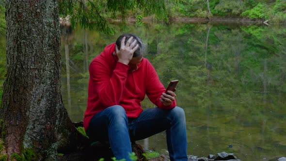 Bearded Man with a Phone Near a Mountain Lake alt