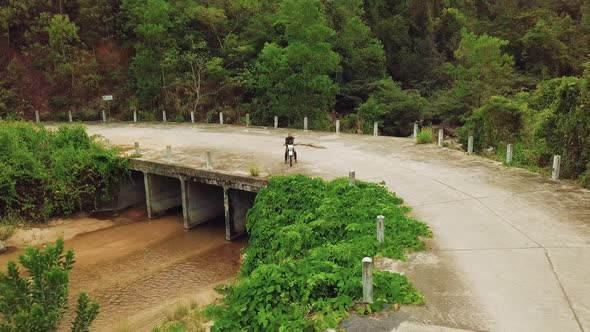 Aerial View of Motorbiker with Bike Parking on Bridge in the Jungle River. alt