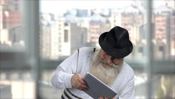 Old Bearded Man Playing Video Game As a Child on a Tablet Pc alt
