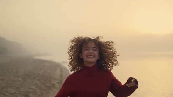 Happy Girl Dancing on Ocean Beach at Sunrise alt