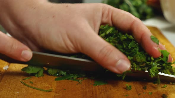 A close-up of the cook slicing parsley. Using a knife and his hand, he kills it from the kitchen alt