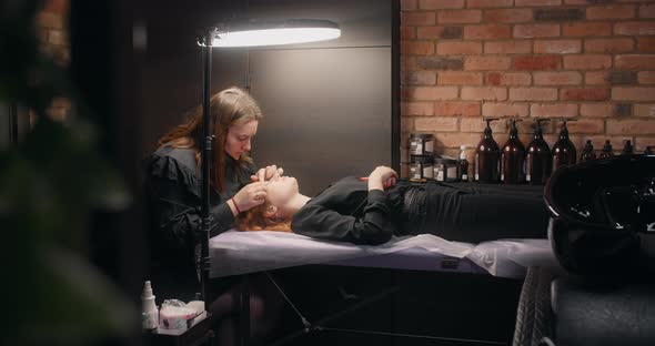 Lashmaker Does the Eyelash Lamination Procedure for the Client in the Beauty Salon Cosmetic Services alt