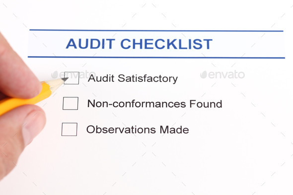 Audit checklist and human hand with pencil