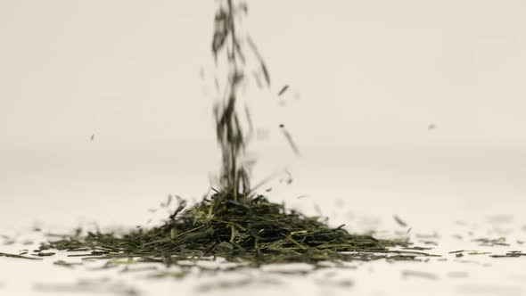 Macro shot of tea leaves fall on a pile of a green tea