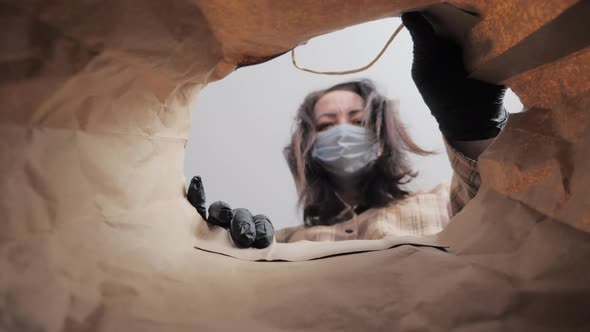 Young Woman with Personal Protective Equipment Gloves and a Medical Mask on Facecarefully Opens Box alt