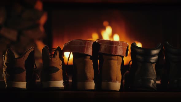 A Few Pairs of Winter Shoes Are Drying Near the Fireplace Where the Fire Is On alt
